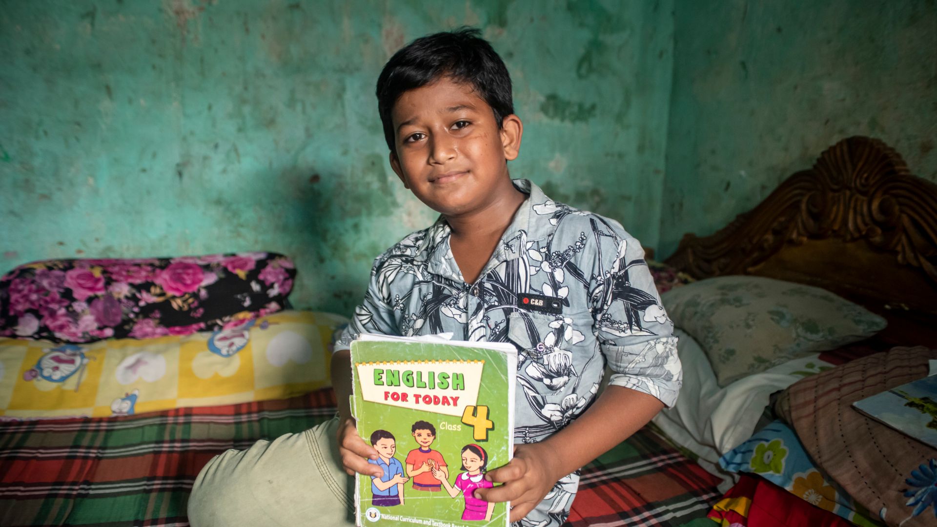 Child with book, doorstep learning, working children, Sylhet, Bangladesh